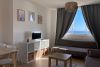 Salón con sofá cama y ventanales con vistas al mar.
