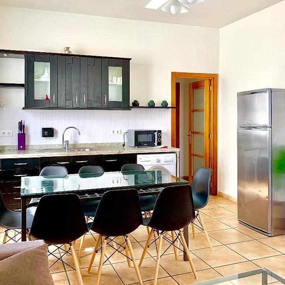 Cocina moderna con comedor amplio en el apartamento Wellness, equipada con electrodomésticos y decoración funcional.
