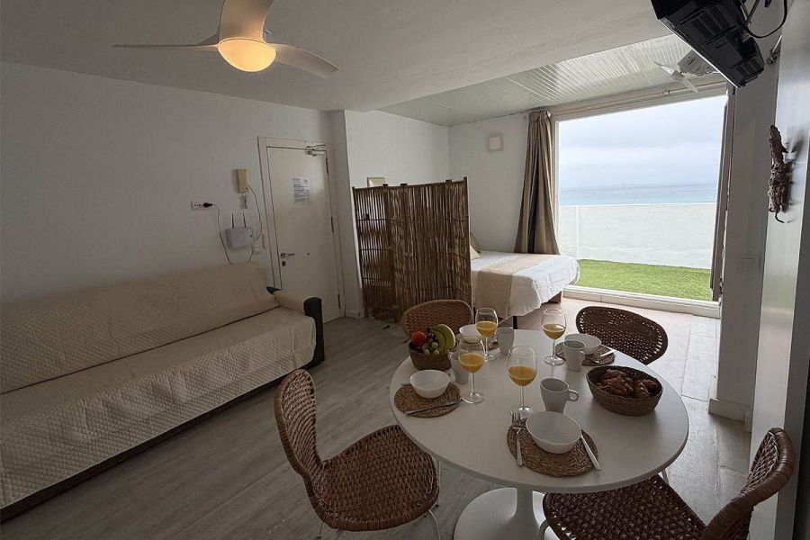 Salón comedor con sofá cama y vistas al mar en apartamento Infinity en Tarifa.