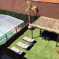 Jardín del Edificio Senses con piscina cubierta, tumbonas y pérgola de madera.