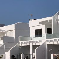 Detalle de las viviendas blancas con terrazas y grandes ventanales en la urbanización Las Cañas.