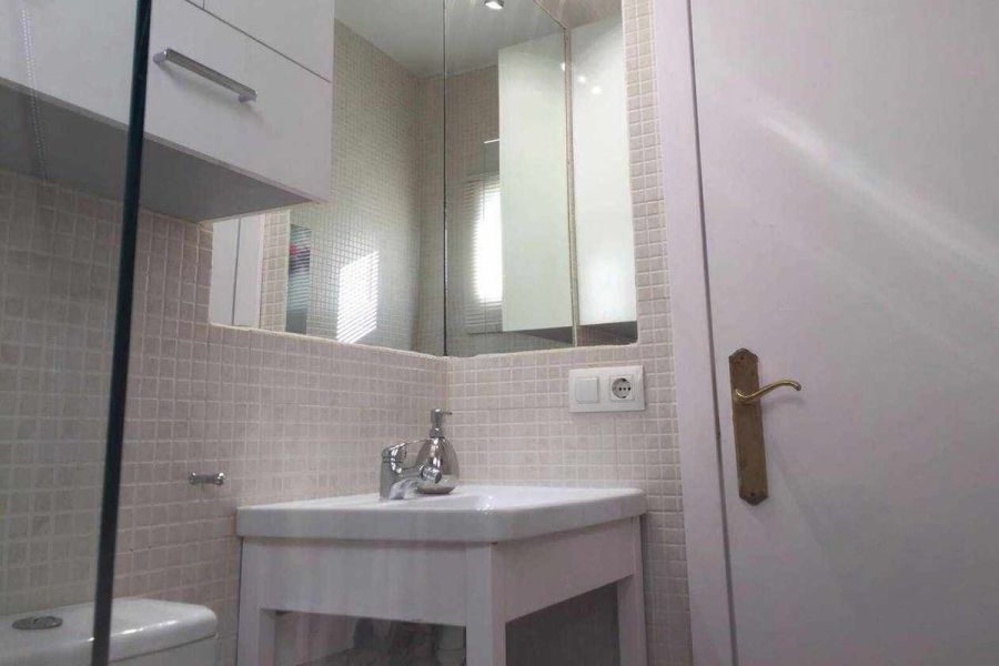 Baño moderno del apartamento Wellness en el edificio Senses, con lavabo y azulejos claros.s
