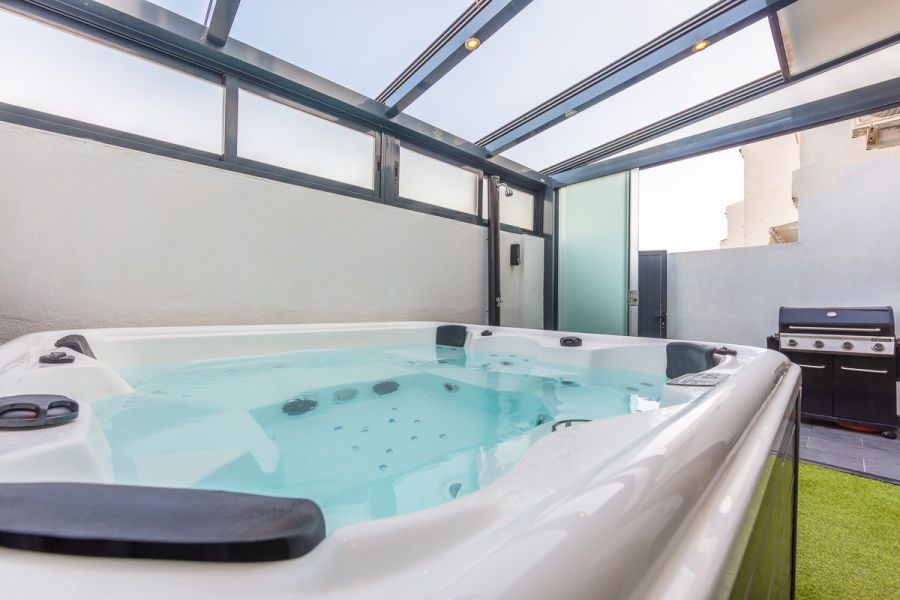 Jacuzzi privado del apartamento Las Gaviotas 9B en Tarifa en patio cubierto con barbacoa exterior y cerramiento acristalado.