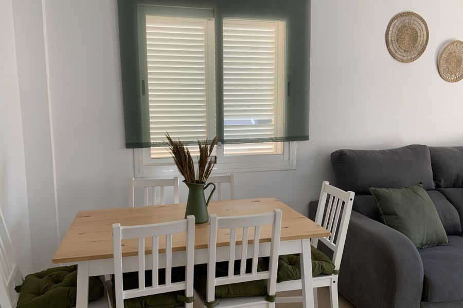 Salón de Los Lances 2 con zona de comedor, sofá chaise longue y decoración en tonos verdes y naturales.