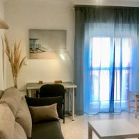 Salón del apartamento Callao con sofá, escritorio y decoración en tonos neutros con detalles cálidos.