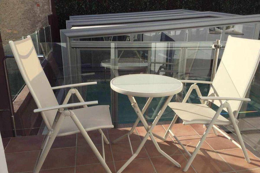 Terraza privada del apartamento Wellness con mesa y sillas, junto a la piscina cubierta.