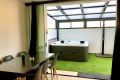 Zona cubierta con jacuzzi, césped artificial y mesa de comedor para disfrutar en el adosado Las Gaviotas.