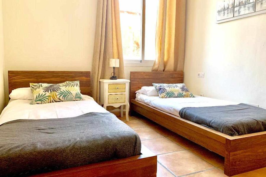 Dormitorio con dos camas individuales en el apartamento Wellness, decorado con estilo cálido y natural.