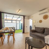 Salón comedor del apartamento Las Gaviotas 9B en Tarifa con sofá, mesa de comedor y vistas directas al patio con jacuzzi privado.