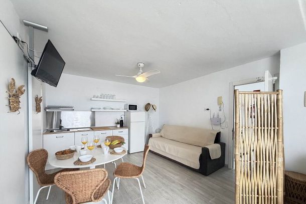 Salón con cocina abierta, comedor y sofá cama en apartamento Infinity en Tarifa.