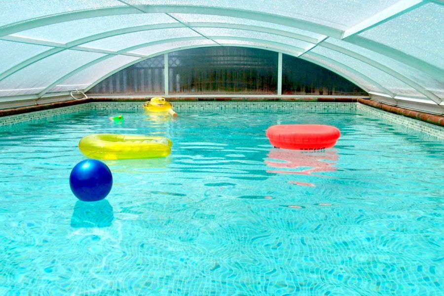 Piscina cubierta de Villa Paraíso en el chalet La Ahumada, con flotadores de colores y agua cristalina para disfrutar en cualquier temporada.