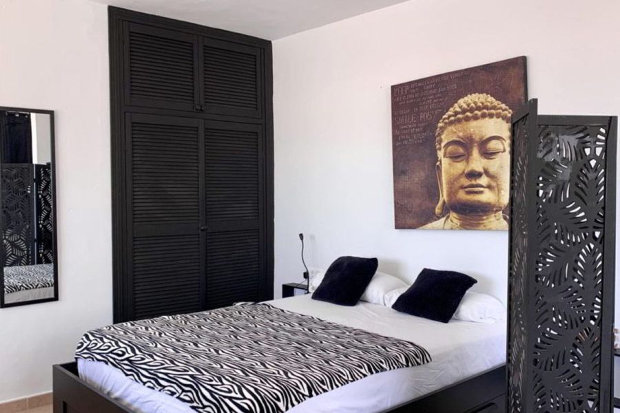 Cama doble del Estudio Senses con armario negro y cabecero decorativo.