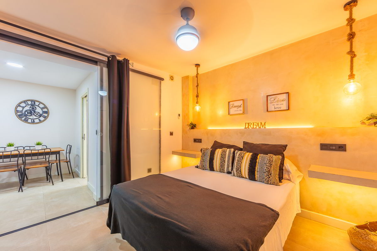 Espacio de descanso con cama doble, iluminación cálida y acceso visual a la zona de comedor del apartamento Las Gaviotas 9B en Tarifa.